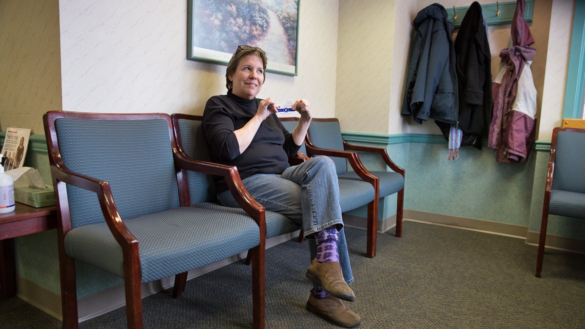  Suzanne Cloud, executive director of Jazz Bridge is on a mission to get musicians to sign up for Affordable Care Act.  She shows off her new health insurance cards as she waits to be seen by her doctor at Cooper Medical Services in Cherry Hill, N.J. (Lindsay Lazarski/WHYY) 