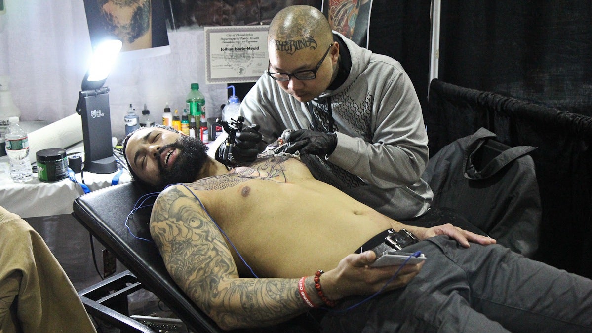 Josh Harle-Mould tattoos a sacred heart on Louis Odon's chest. (Kimberly Paynter/WHYY)