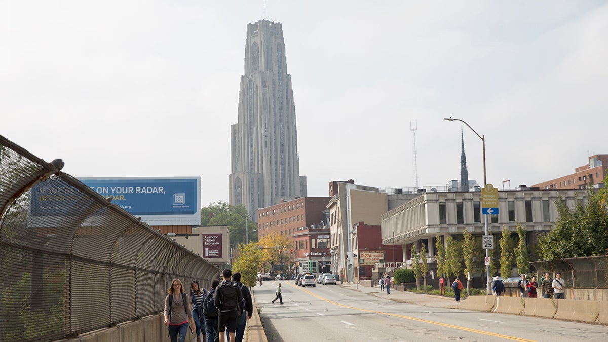  Pedestrians cross a bridge near the campuses of Carnegie Mellon University and the University of Pittsburgh. Hospitals and universities are among organizations that count as charities in Pennsylvania and, as such, don't pay property taxes. (Lindsay Lazarski/WHYY) 