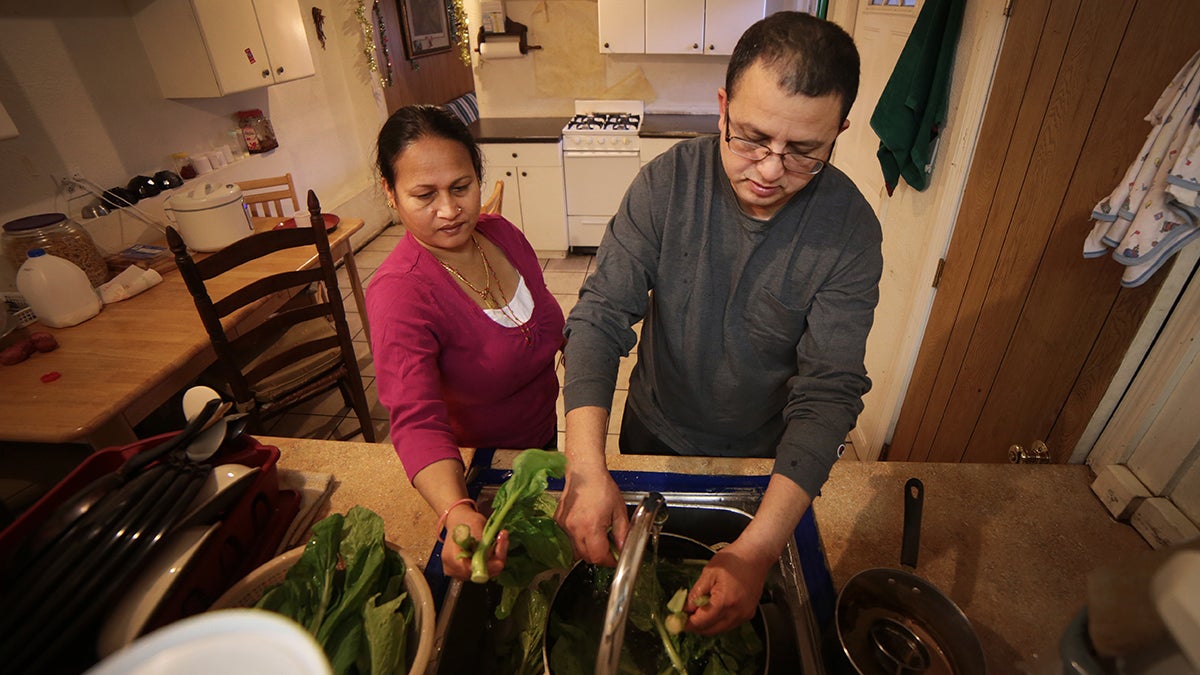  Tek Nepal (right) washes spinach at his Mount Oliver home with his wife Radhika Nepal last winter. Tek Nepal is ethnically Nepalese. He was resettled in California as a refugee, moved to Tennessee, then Pittsburgh, which has a lower cost of living and boasts an increasingly growing Bhutanese-Nepalese population. Pittsburgh wants to encourage more immigrants to settle in the city. (Ryan Loew/WESA) 