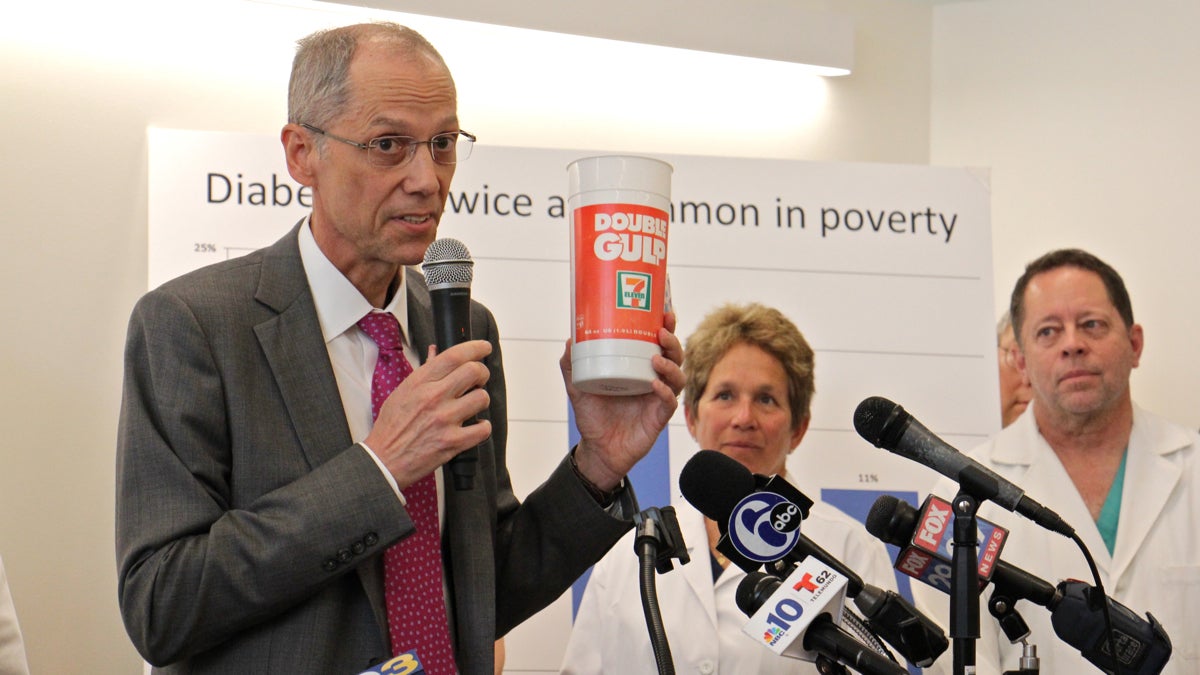 Philadelphia Health Commissioner Thomas Farley holds up a Double Gulp soda container during a press conference at Puentes de Salud Health Clinic where doctors gathered to tout the health benefits of the sugary drinks tax. (Emma Lee/WHYY)