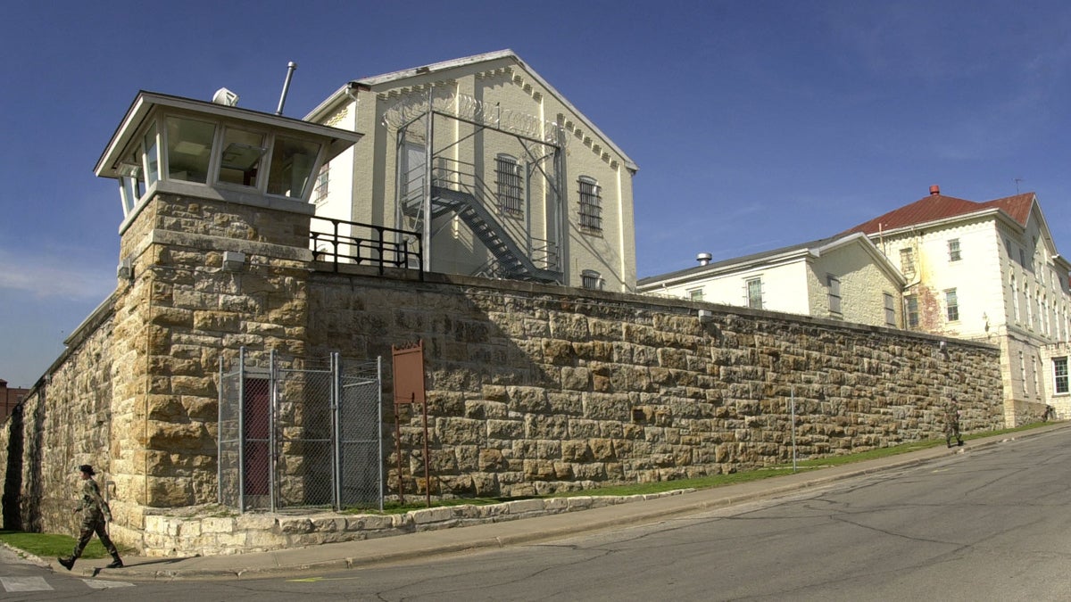 A soldier walks past a stone wall surrounding the U.S. Disciplinary Barracks at Fort Leavenworth