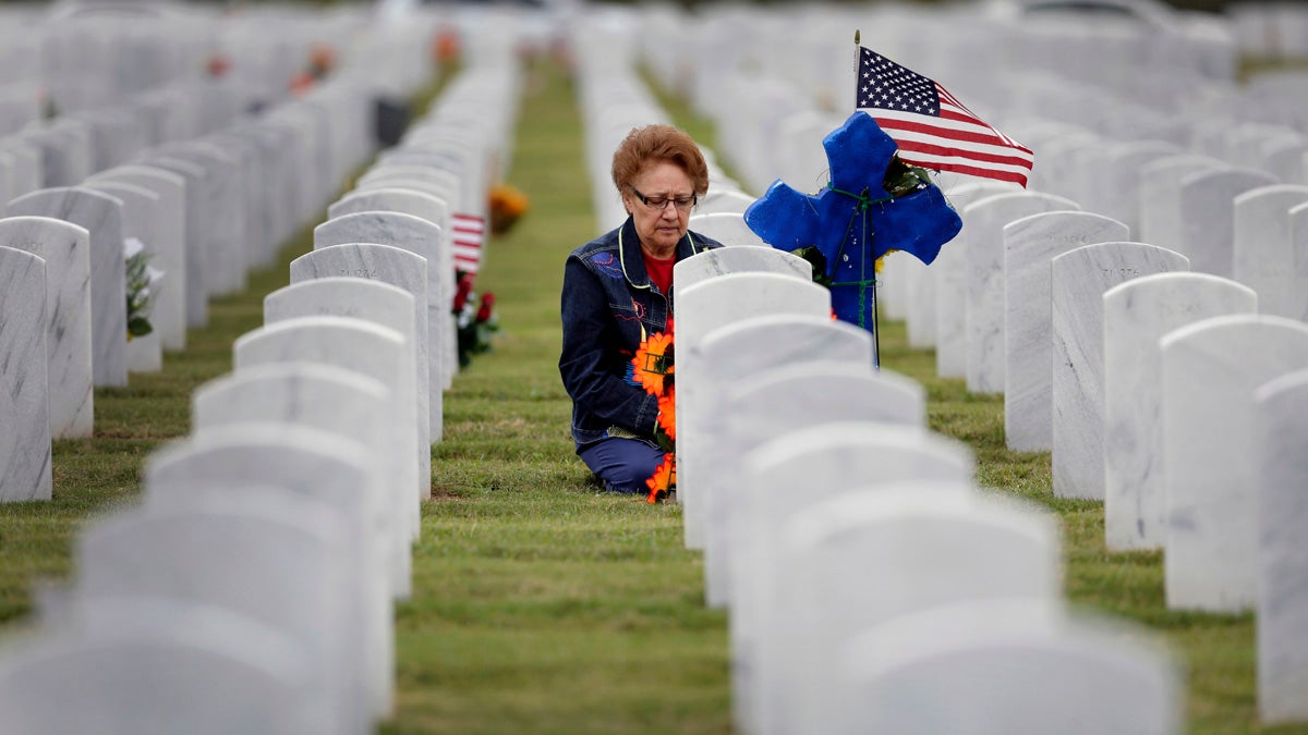  A woman knees at a headstone after placing an American flag and cross at Fort San Houston National Cemetery, Tuesday, Nov. 11, 2014, in San Antonio. (AP Photo/Eric Gay) 