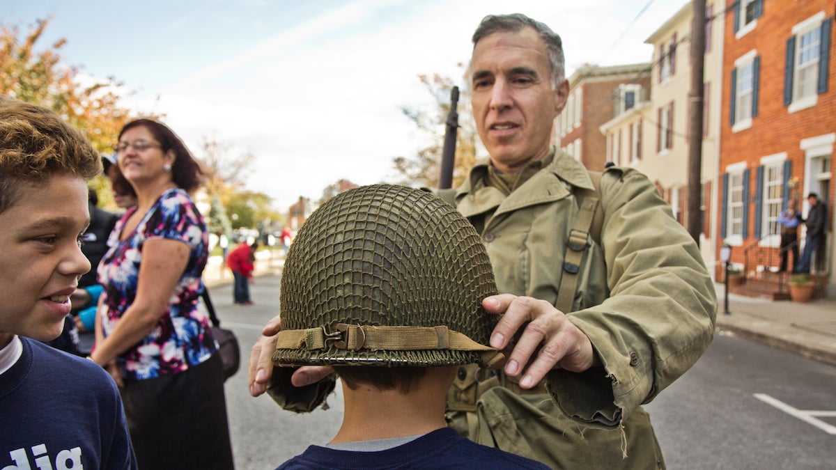 Joe Solari, National Guard, 1977-1981, places his helmet on Ben Liedman of Media Elementary. (Kimberly Paynter/WHYY)