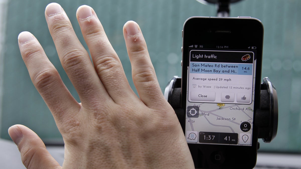 A driver waves his hand over a traffic and navigation app called Waze on his Apple iPhone. (AP Photo/Paul Sakuma