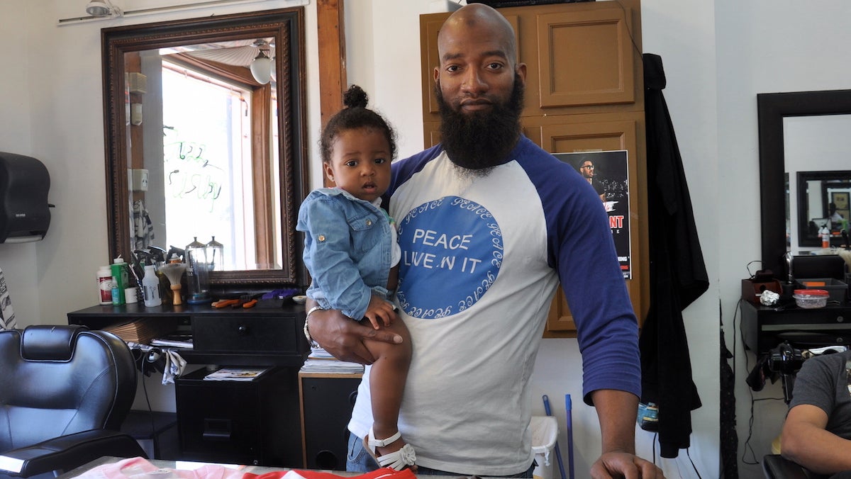  Will Little sells most of his shirts at Jazz U Up in South Philly. On his shoulder is his daughter, Sophia. (Greta Iverson/for NewsWorks) 