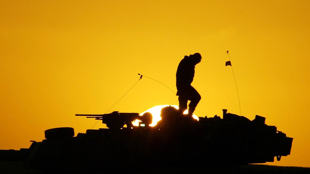  A U.S. soldier walks atop his armored vehicle at sunset as he  prepares for a night military exercise, in the Kuwaiti desert south of the Iraqi border, Sunday, Dec. 22, 2002. (AP Photo/Anja Niedringhaus, file) 