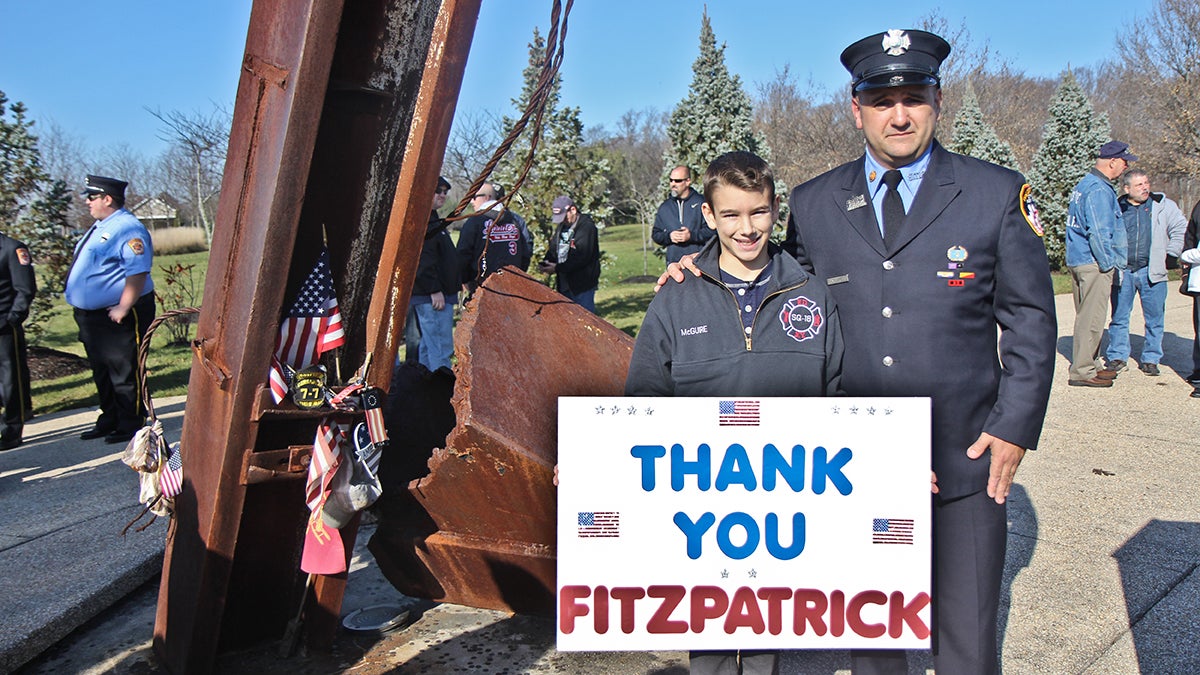  NY firefighter Brian McGuire and his son Collin stand next to a 9/11 Memorial to support the James Zadroga 9/11 Health and Compensation Reauthorization Act. (Kimberly Paynter/WHYY) 