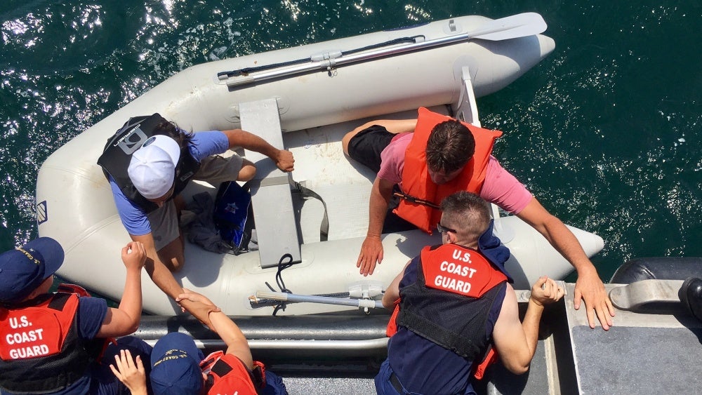  U.S. Coast Guard members help rescue two passengers from a capsized boat off the New Jersey coast Friday morning. (Image courtesy of Sabrina Clarke/U.S. Coast Guard) 