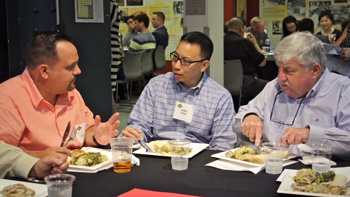 John Chin (center), executive director of the Philadelphia Chinatown Development Corp. shares a meal with mummers Joe Yoa (left) and John Wilson at Reading Terminal Market as part of the Breaking Bread, Breaking Barriers project of the Philadelphia Human Relations Commission. (Emma Lee/WHYY)