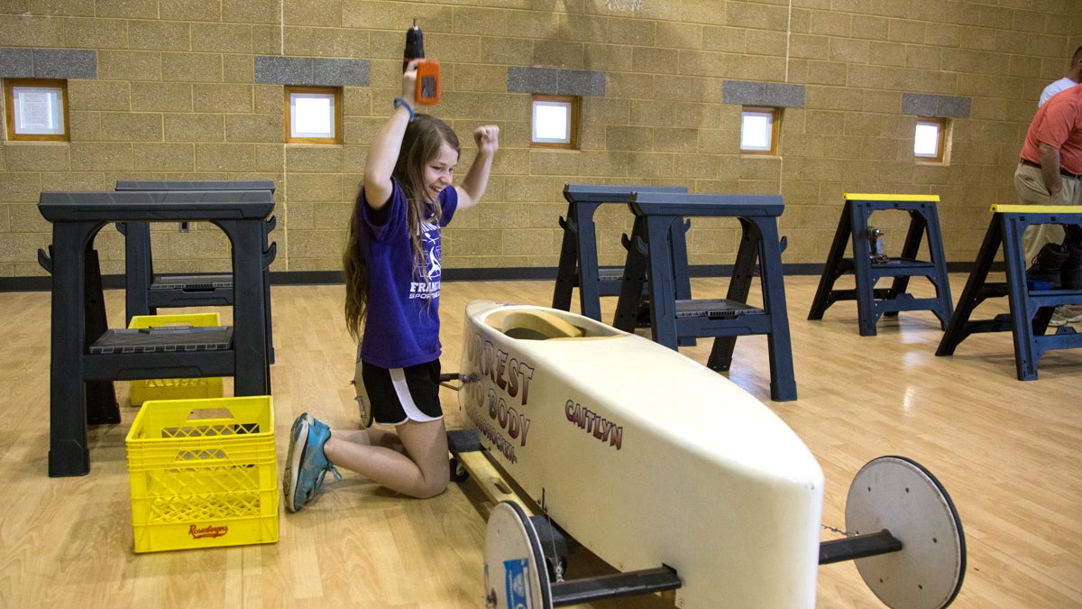 Caitlin Ferrell, 11, cheers for herself after successfully using a power drill on her soap box derby car. This is her third year racing in the Annual Conshohocken Soap Box Derby which takes place every July 4th. (Emily Cohen for NewsWorks)