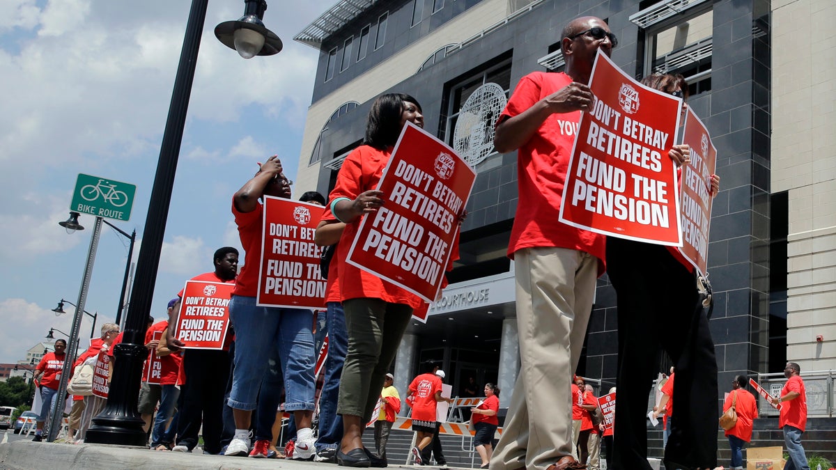 Union members carry protest signs as they march outside the Mercer County Criminal Courthouse before arguments June 25, 2014, over Gov  Christie's plan to use pension payments to balance the budget. (AP Photo/Mel Evans) 