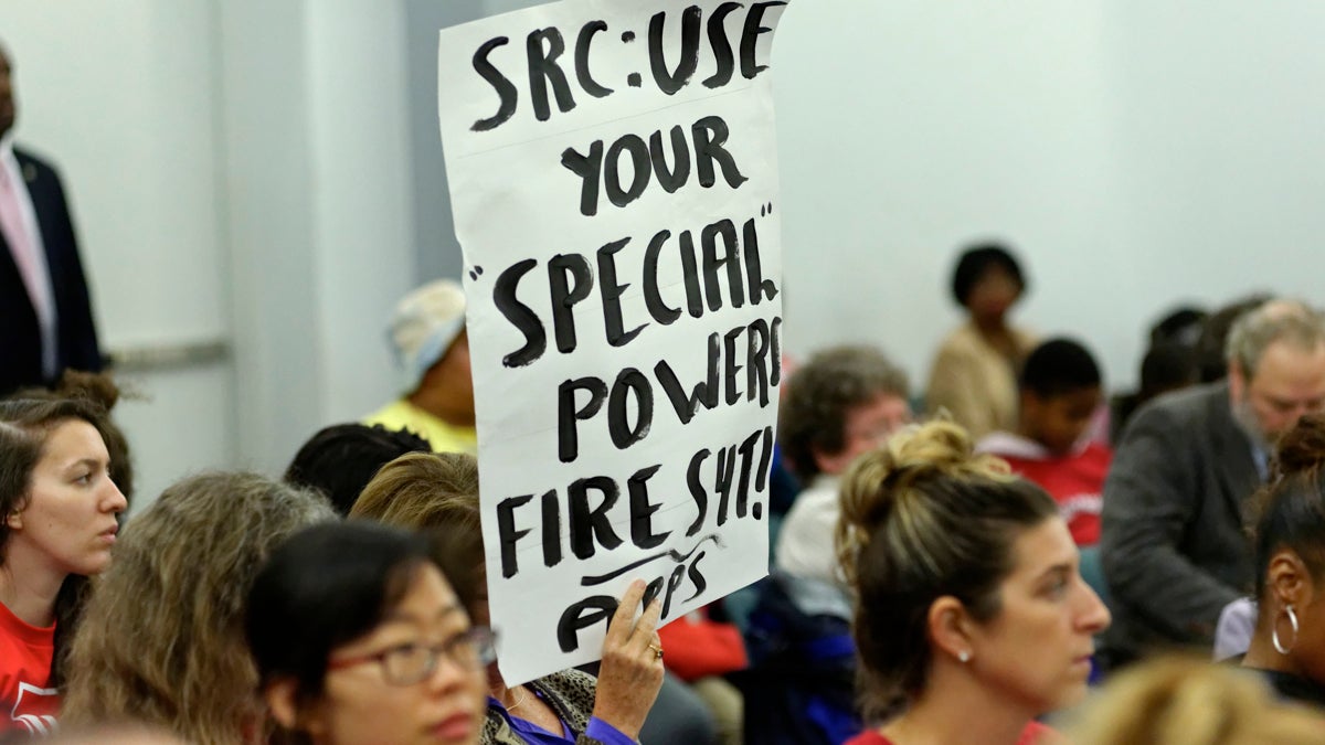  An attendee at November's SRC meeting holds a sign urging the board to get rid of Source4Teachers. (Bastiaan Slabbers/for NewsWorks) 