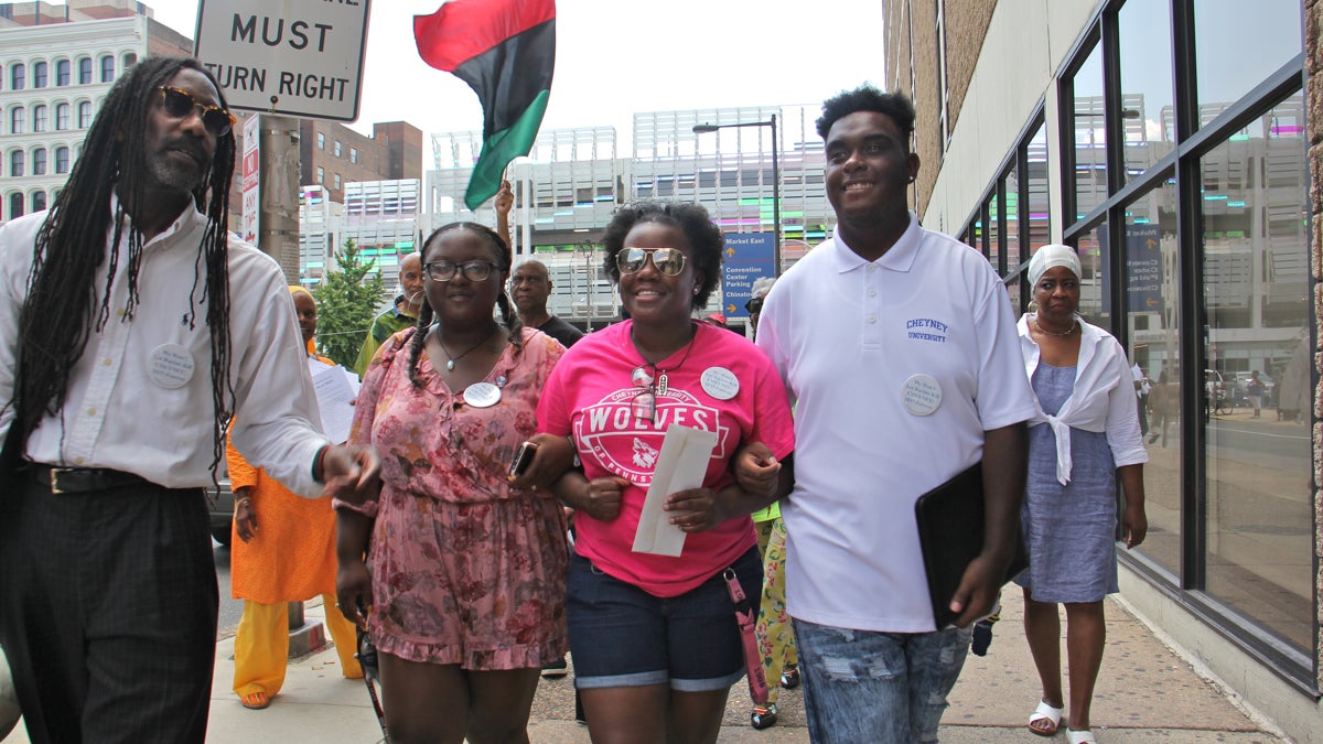  Cheyney students (from right) Shaquille Harrison, Nyrie Watson and Shaneka Briggs link arms as they make their way to Gov. Tom Wolf's Philadelphia office on Eighth Street to deliver a letter demanding funds for the struggling historically black university. (Emma Lee/WHYY) 