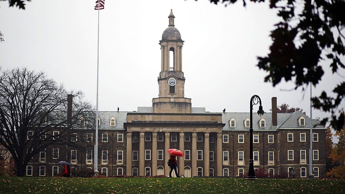 A Penn State student walks in the rain past Old Main on the Penn State main campus in State College, Pa., Wednesday, Oct. 28, 2015. (AP FILE Photo/Gene J. Puskar) 