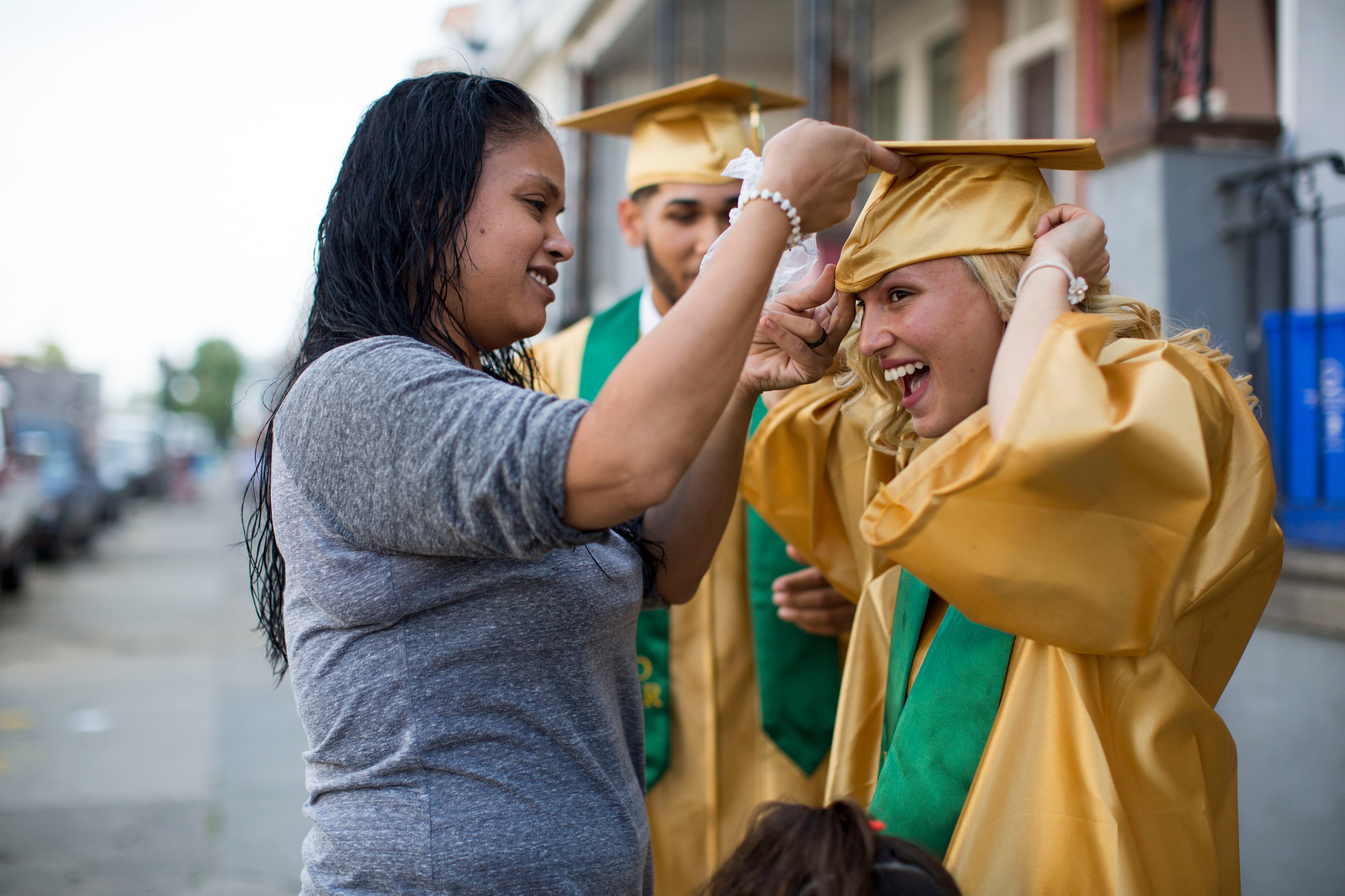 Neverlyn, who dropped out of Thomas A. Edison High School 20 years ago, helps Savannah fit her graduation cap. (Jessica Kourkounis/For Keystone Crossroads)