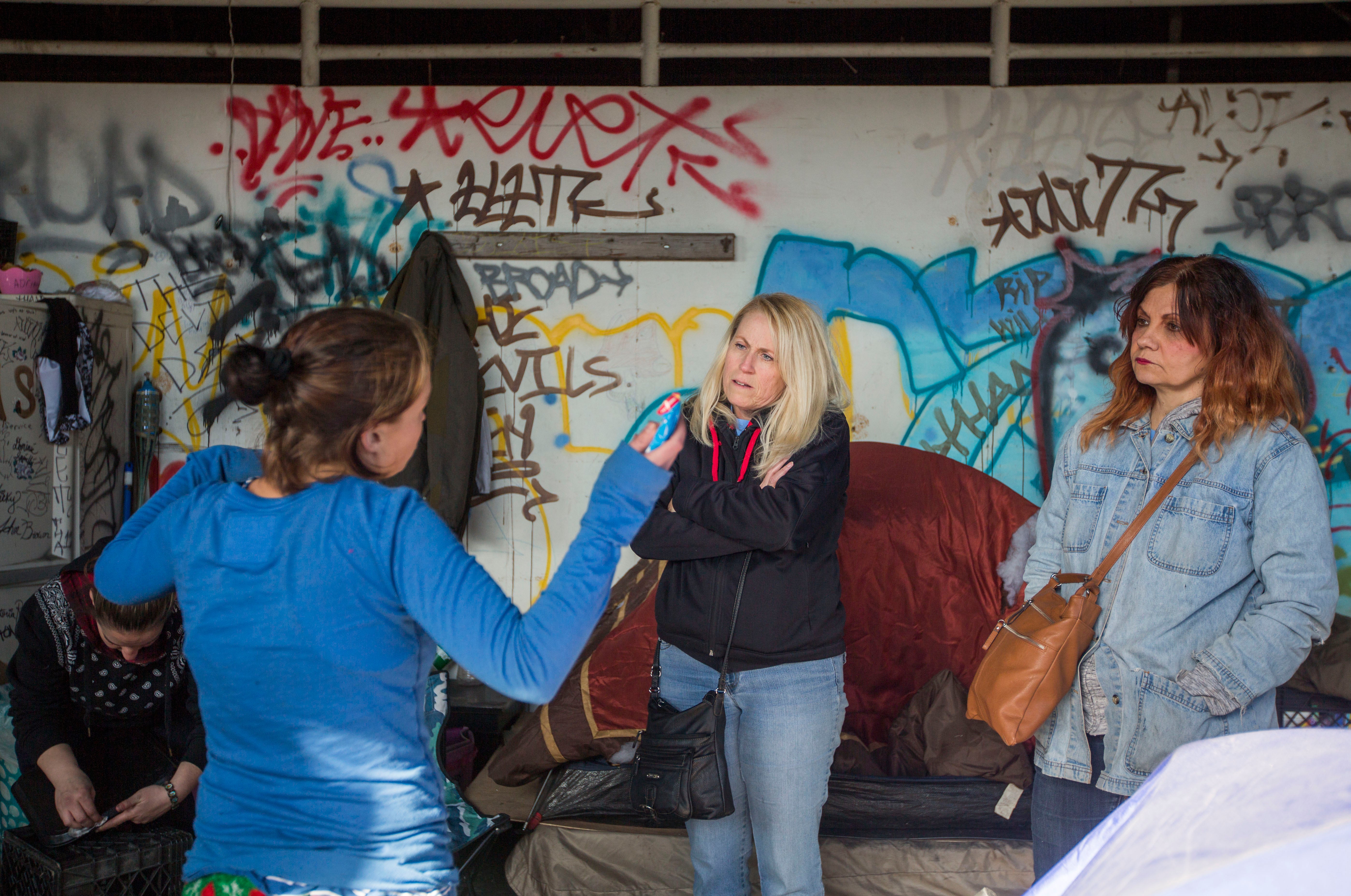 Carol Rostucher (center) and Barb Burns talk to a homeless woman living in an abandoned building in Kensington in Philadelphia. Jessica Kourkounis/For Keystone Crossroads)