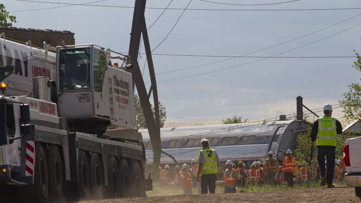 Emergency personnel bring in a crane to move the derailed Amtrak train near Port Richmond in North Philadelphia Wednesday morning. (Brad Larrison/for NewsWorks)