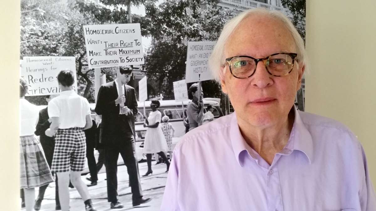 John S. James stands beside a photo of himself taken during the July 4, 1965, demonstration for gay rights at Independence Hall. (Peter Crimmins/WHYY)