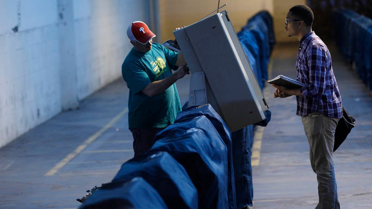 Technician Tom Mattia Jr. (left) and Malcolm Kenyatta test a voting machine in 2011 in Philadelphia. (Matt Rourke/AP Photo)