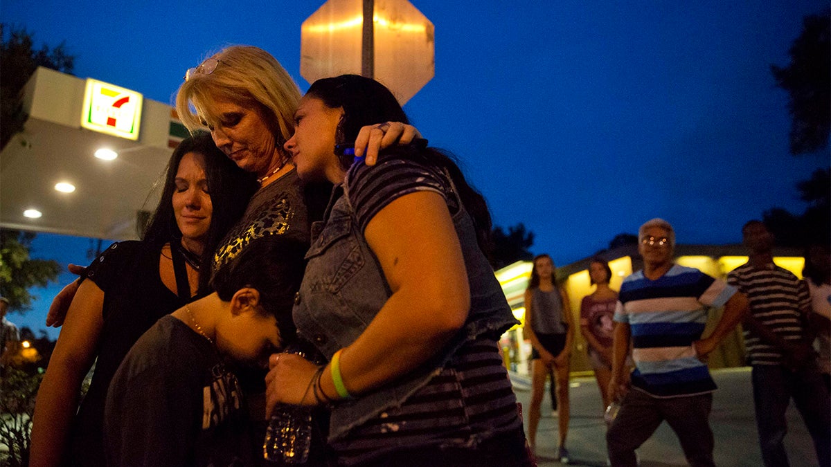 Elsie Allen, center, huddles with her daughters Jenna Allen, right, and Krista Allen-Parra, left, and her grandson Shawn Flores, all of Orlando, as they visit for the first time the scene of the Pulse nightclub mass shooting from a block away Friday, June 17, 2016, in Orlando, Fla. (AP Photo/David Goldman) 