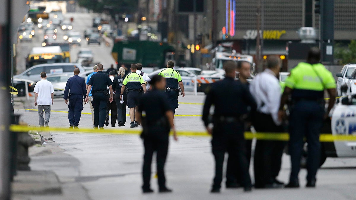 Investigators walk the scene of a shooting in downtown Dallas