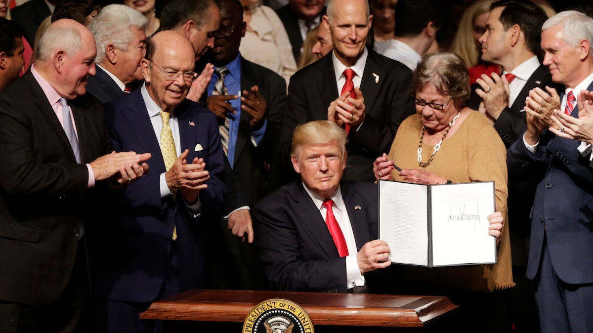  President Donald Trump shows the signed executive order surrounded by cabinet members and supporters in Miami, Friday, June 16, 2017. Trump announced a revised Cuba policy aimed at halting the flow of U.S. cash to the country's military and security services while maintaining diplomatic relations. From left are, Agriculture Secretary Sonny Perdue, Commerce Secretary Wilbur Ross, the president, Florida Gov. Rick Scott, Cary Roque, a Cuban political dissident, and Vice President Mike Pence. (AP Photo/Lynne Sladky) 