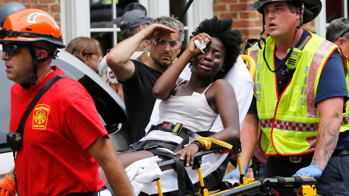 Rescue personnel help an injured woman after a car ran into a large group of protesters after an white nationalist rally in Charlottesville, Va., Saturday, Aug. 12, 2017. (AP Photo/Steve Helber)