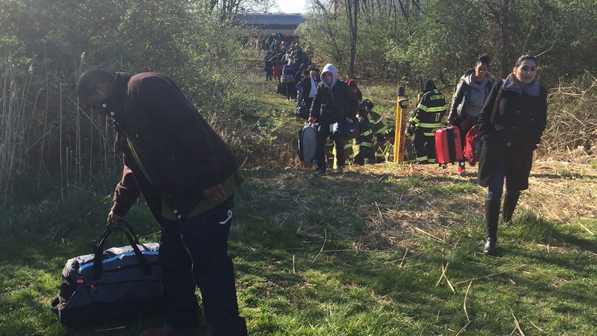 Passengers leave an Amtrak train following a deadly crash Sunday in Chester, Pennsylvania. The Amtrak train struck a piece of construction equipment just south of Philadelphia, killing two workers and causing a derailment.