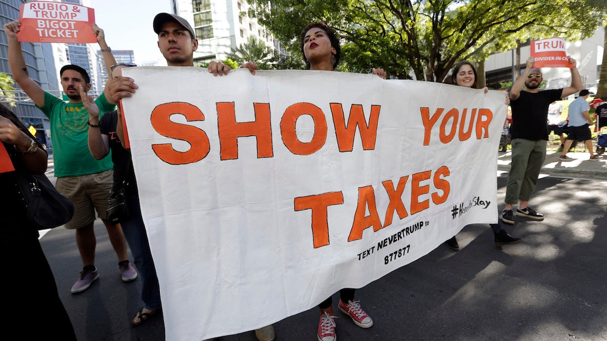 Protestors march in a downtown street holding a sign in support of Republican presidential candidate Donald Trump releasing his tax returns