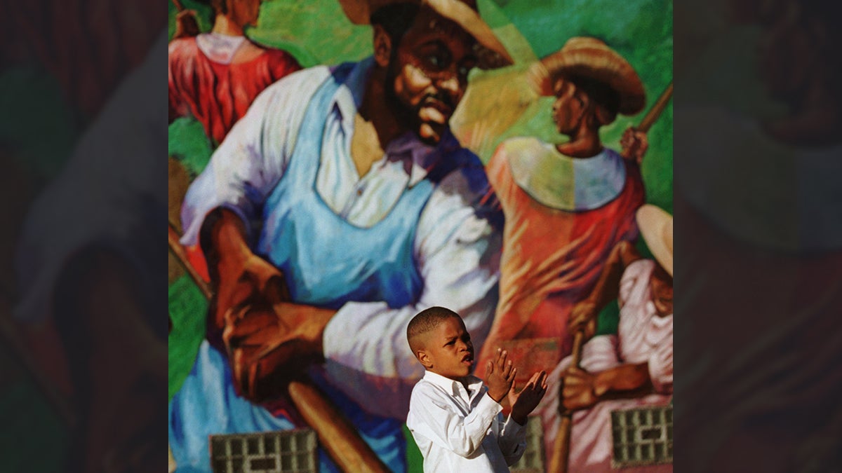  Marlin Hardy, 5, claps to get the attention of teachers as the field hands in the mural 