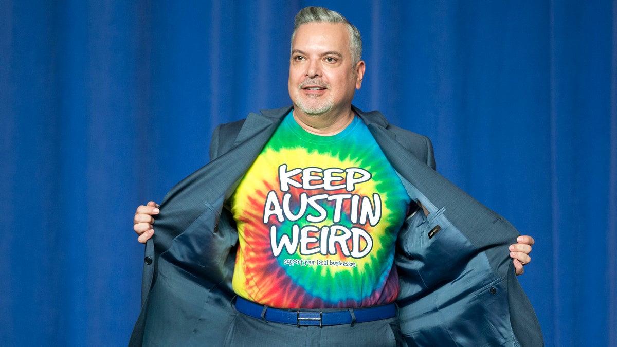  DNC Finance Chairman Henry Munoz, opens up his suit jacket to reveal his 'Keep Austin Weird' tie-dye t-shirt, on stage before introducing President Barack Obama at DNC fundraiser at the Austin Music Hall in Austin, Texas, Friday, March 11, 2016. (Pablo Martinez Monsivais/AP Photo) 