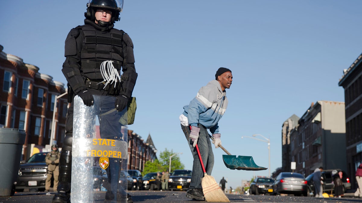  Baltimore residents clean streets as law enforcement officers stand guard Tuesday in the aftermath of rioting following Monday's funeral of Freddie Gray, who died in police custody. (Matt Rourke/AP Photo)  