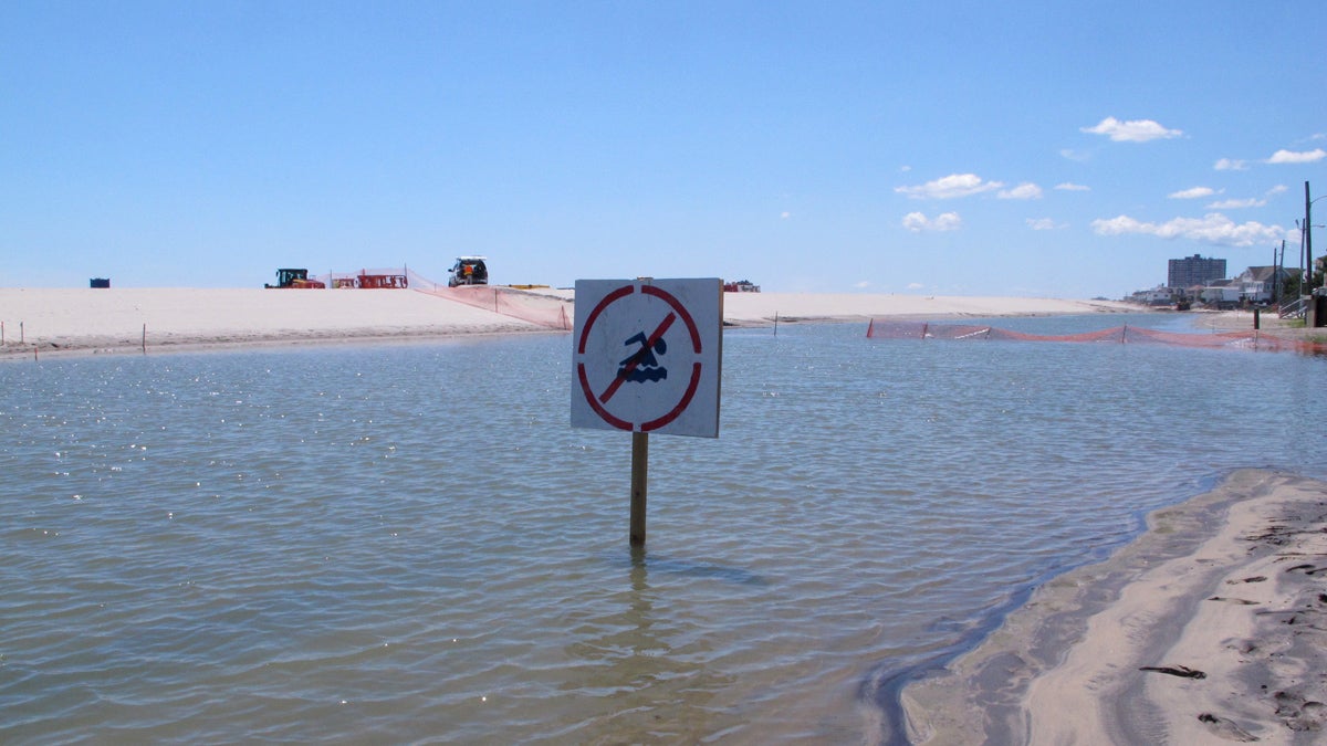  This July 31, 2017 photo shows a no swimming sign in one of numerous large pools of water that have formed on the beach in Margate N.J. due to heavy rains. The water is blocked from draining into the ocean by new sand dunes being built as part of a storm protection program that Margate residents vigorously fought, claiming that the dunes would cause exactly the type of standing water that has occurred. (Wayne Parry/AP Photo) 