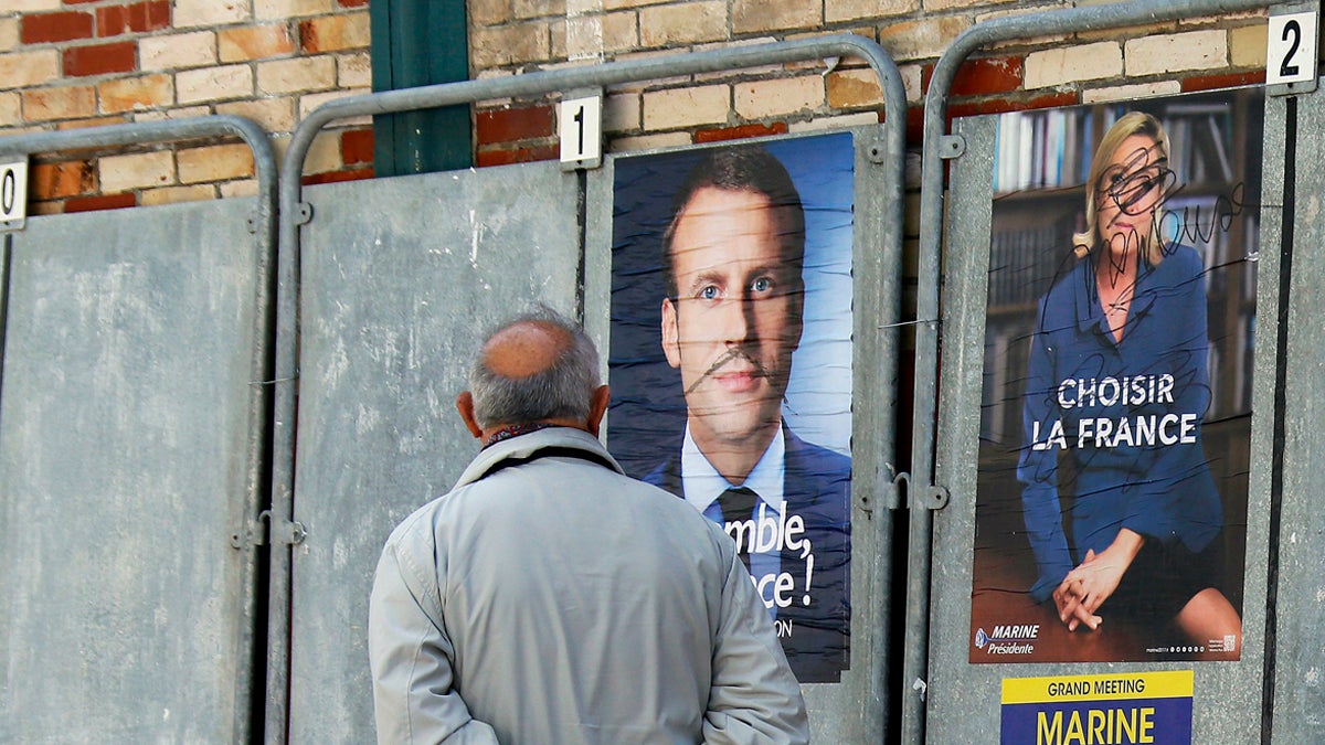  A man walks past defaced election campaign posters for French centrist presidential candidate Emmanuel Macron and far-right candidate Marine Le Pen, in Saint Jean de Luz, southwestern France, Thursday, May 4, 2017. France vote Sunday May 7 for the second round of the presidential election. (Bob Edme/AP Photo) 