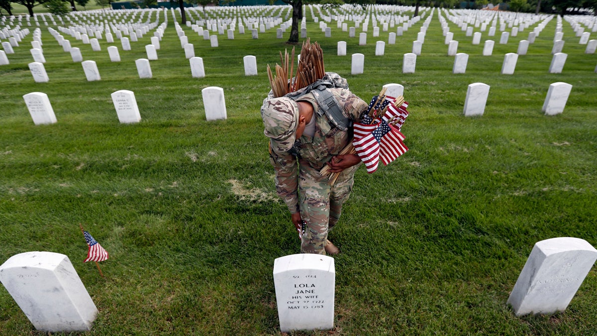  U.S. Army Staff Sgt. Anthony Ellis with the 3d U.S. Infantry Regiment (The Old Guard), places a flag at a headstone for 