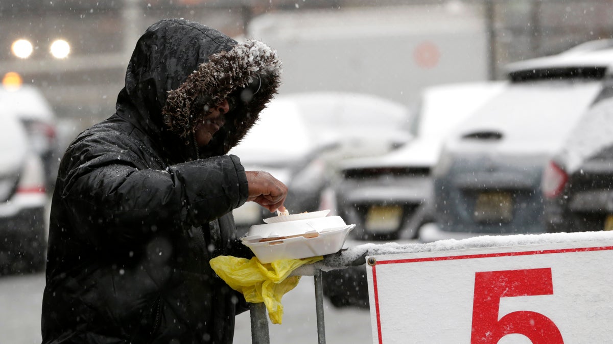 Snow falls over a homeless person while eating a pre-Thanksgiving meal from the St. John's Church soup kitchen