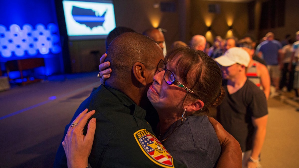 East Baton Rouge Sheriff officer Eddie Guidry is hugged by a teary Terri Carney, both members of The Rock Church which is a ministry on the outskirts of Baton Rouge, during a prayer vigil for the officers killed and wounded by a gunman on Sunday as well as members of the local law enforcement community in Zachary, La., Monday, July 18, 2016. About 100 people came to the special hour long prayer vigil. (AP Photo/Max Becherer)