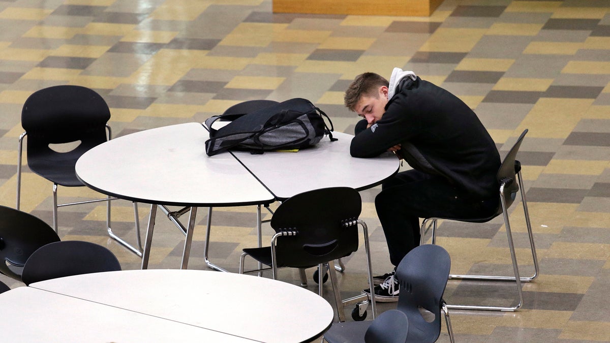 In this photo taken Nov. 23, 2015, a student leans on a table in the cafeteria during first period at Roosevelt High School in Seattle. More school districts around the U.S. are heeding the advice of scientists who have long said that pushing back school start times can improve student health or academic output. (Elaine Thompson/AP Photo) 