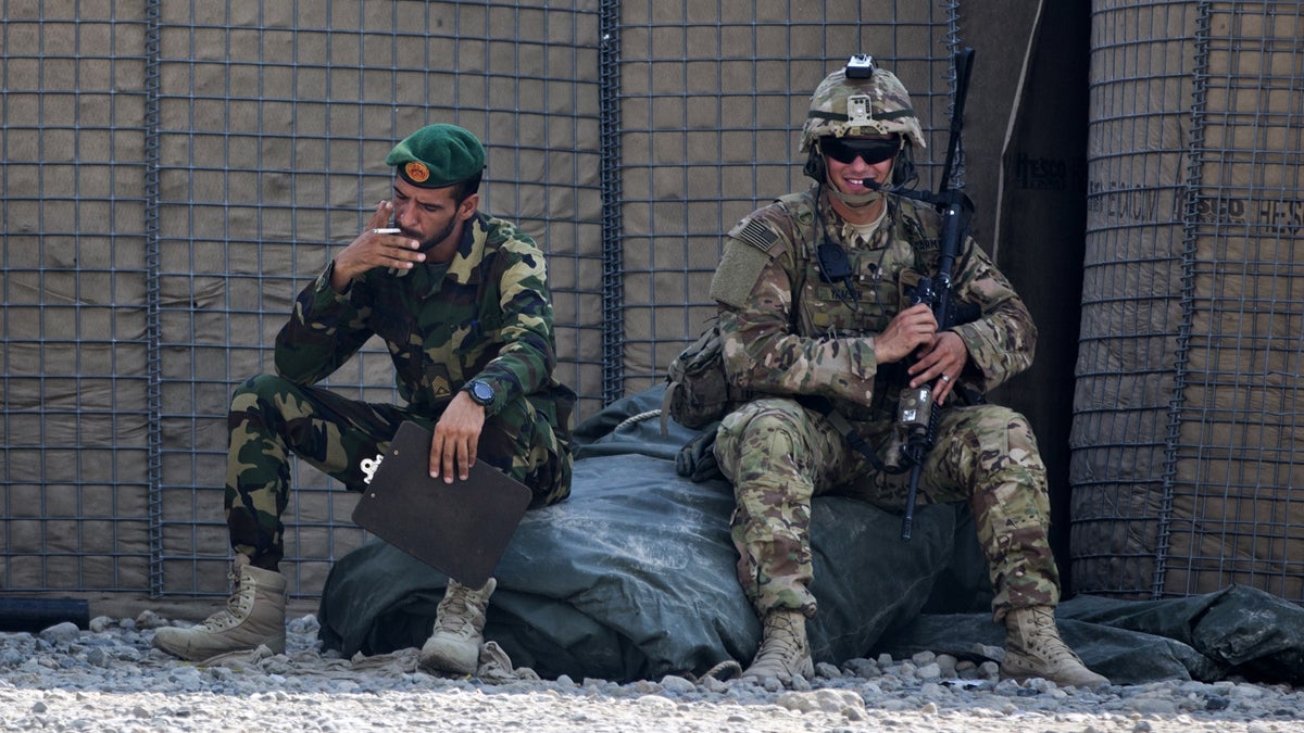  In this Wednesday, Aug. 5, 2015 file photo, Afghanistan's National Army soldier smokes as a U.S. Army soldier from Charlie Company, 2-14 Infantry Regiment, 2nd Brigade, 10th Mountain Division sits next to him in Camp Khogyani in Nangarhar province, east of Kabul, Afghanistan (Massoud Hossaini/AP Photo) 