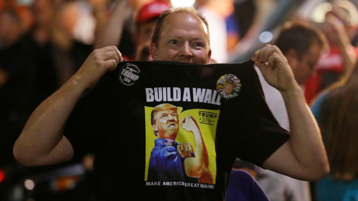  A supporter of Republican presidential candidate Donald Trump holds up his shirt, which bears the Trump slogan 