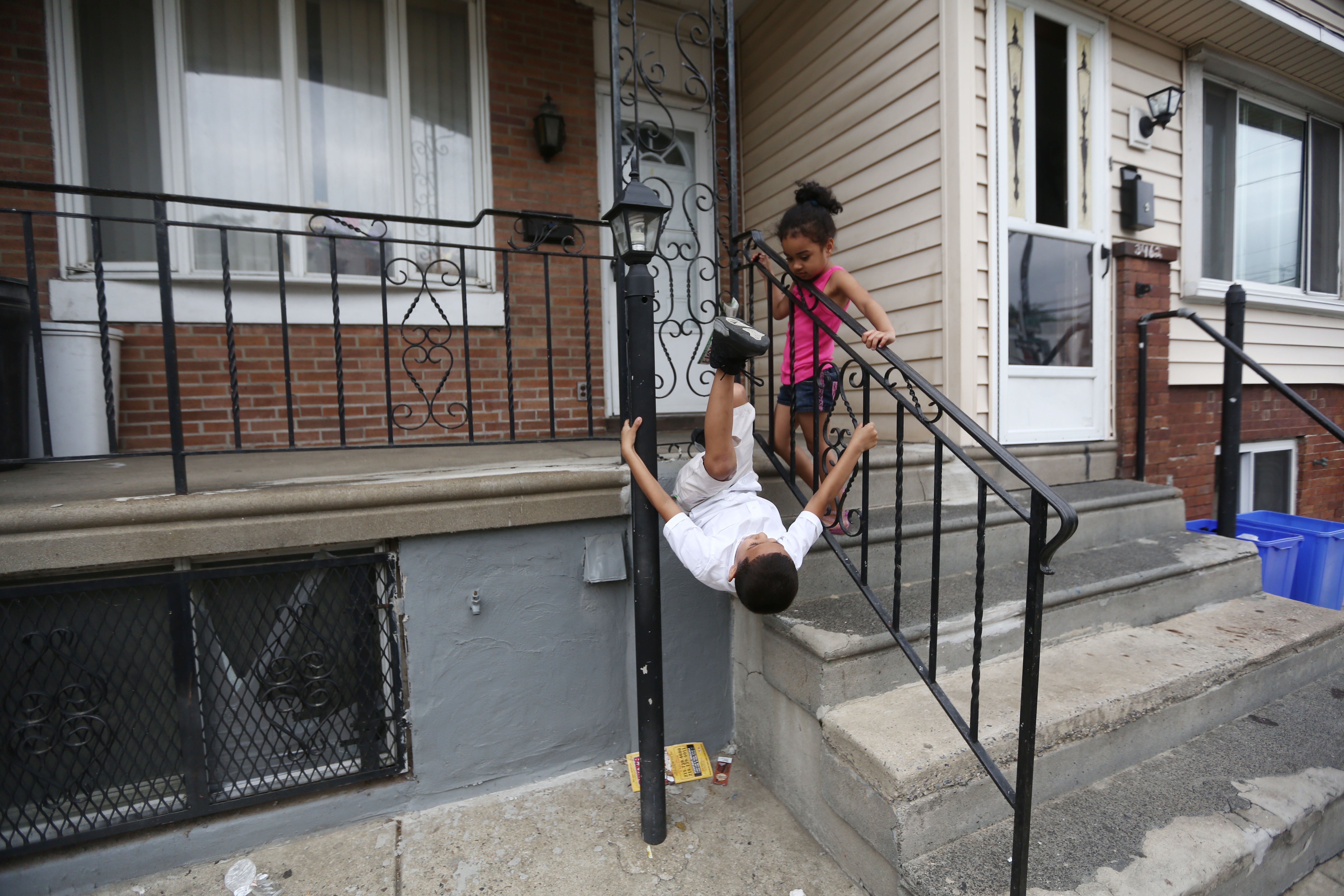 Children on Savannah’s block in Kensington play on a railing. (Jessica Kourkounis/For Keystone Crossroads)
