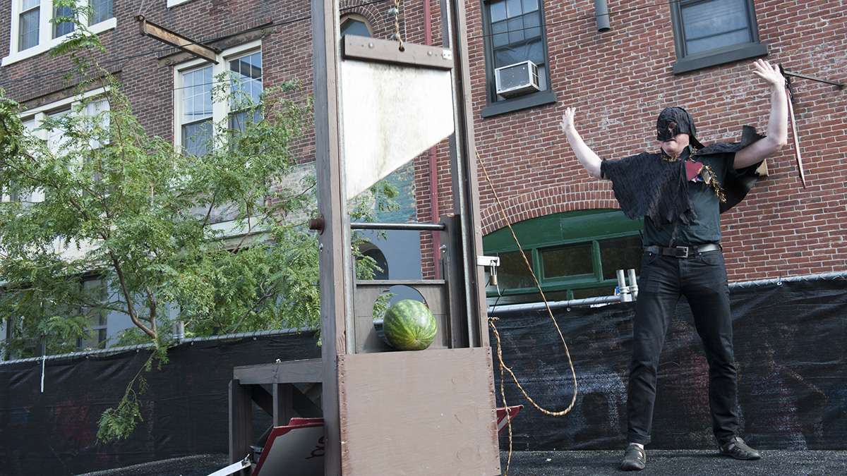 An executioner, portrayed by Eastern State Penitentiary's Sean Kelly, slices watermelons in half with a guillotine.