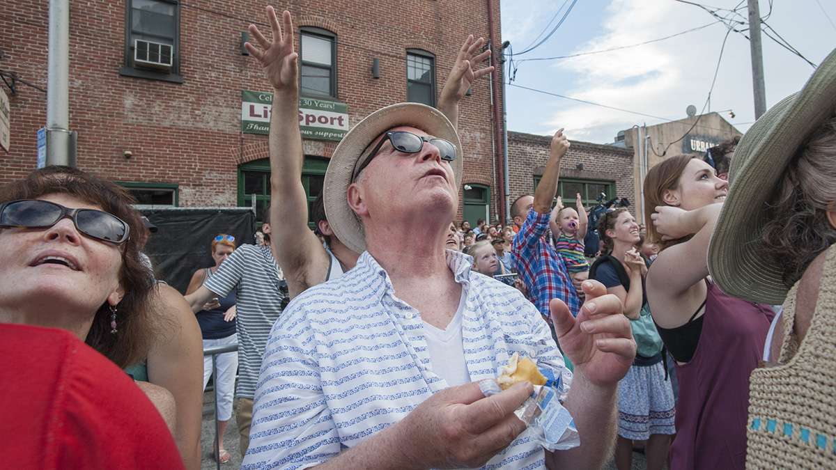 Jim Naughton of Philadelphia nibbles on a Tastykake while other members of the crowd reach skyward to catch one.