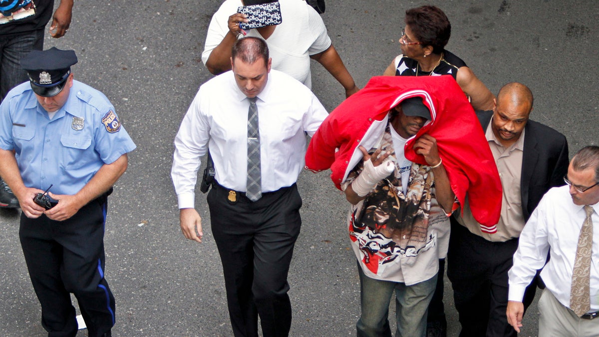 Building Collapse Sean Benschop, with red jacket over his head, is shown on June 8 walking with investigators as he arrives at the Philadelphia Police Department's Central Detectives Division in Center City Philadelphia. (AP Photo/ Joseph Kaczmarek)