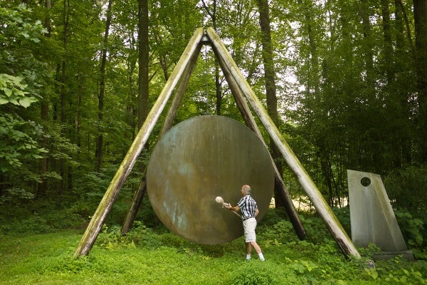 Harry Bertoia's son, Val, demonstrates one of his father's gong sound sculptures outside of his studio in Bally, Pa. (Charlie Kaier/WHYY)