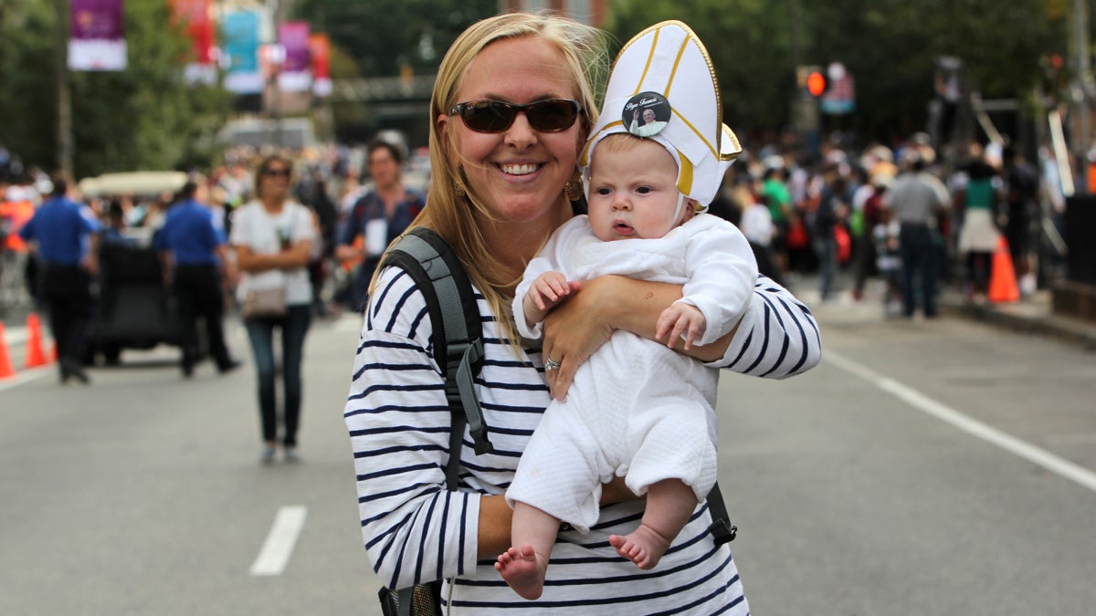 Dana Madden of Yardley holds her 4-month-old daughter Quinn. Madden was standing on 5th Street near Chestnut when the pope 'locked eyes on the baby and started laughing.' He kissed and blessed Quinn. (Emma Lee/WHYY)