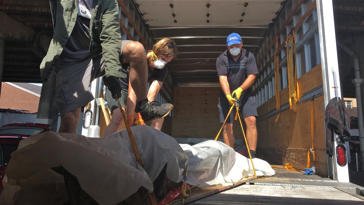  Movers spent Thursday transporting crumbling coffins and other excavated remains from temporary storage units to a central warehouse. (Elana Gordon/WHYY)   