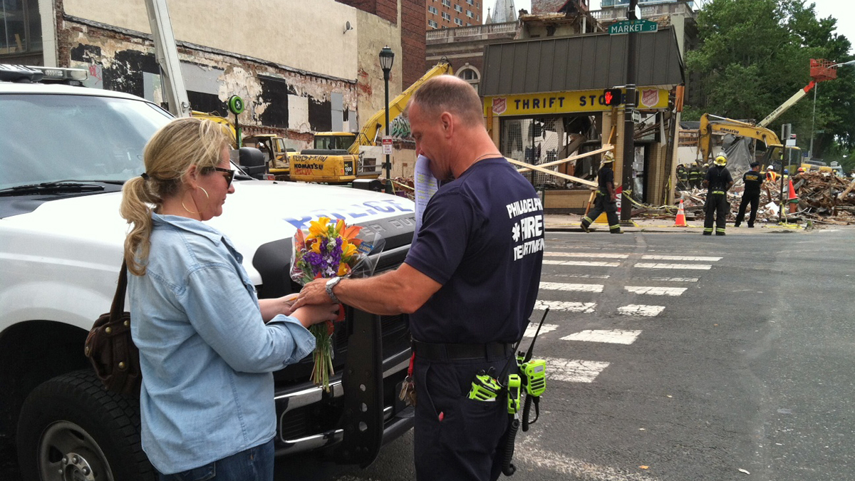  Heather Sizemore brought a bouquet of flowers and handed it to a firefighter to place in the Salvation Army shop. Her friend, Kim Finnegan worked at the store and died in the collapse. She said it was Finnegan's first day at the Market Street site.  (Photo courtesy of Dana DiFilippo/Philadelphia Daily News)Images  
