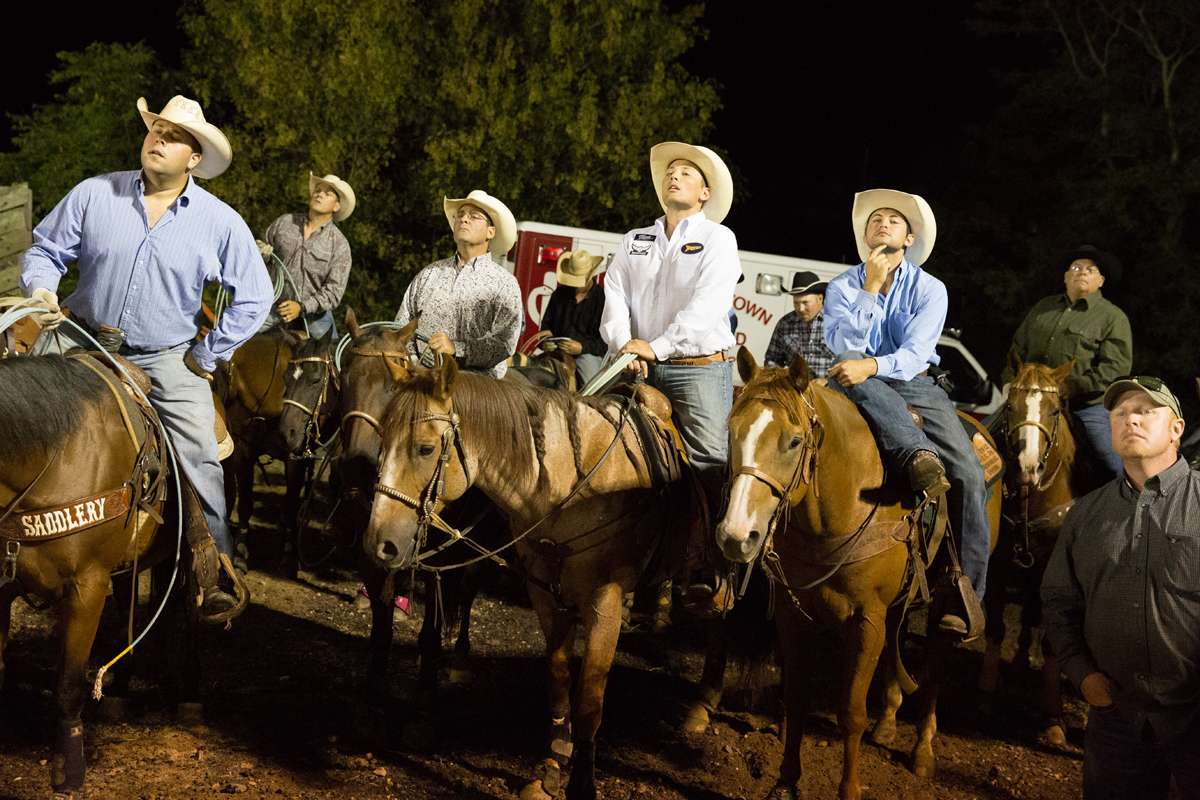 Cowboys look onto the arena from behind the scenes at the Cowtown Rodeo. (Lindsay Lazarski/WHYY)